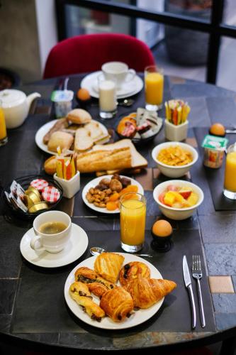 a table with plates of breakfast foods and drinks at Hôtel Lucien & Marinette in Paris