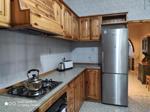 cocina con armarios de madera y nevera de acero inoxidable en Arzella Holiday Home, en Birżebbuġa