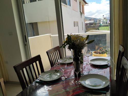 a table with plates and glasses and a vase with flowers at La Casa de Justi in Huancayo