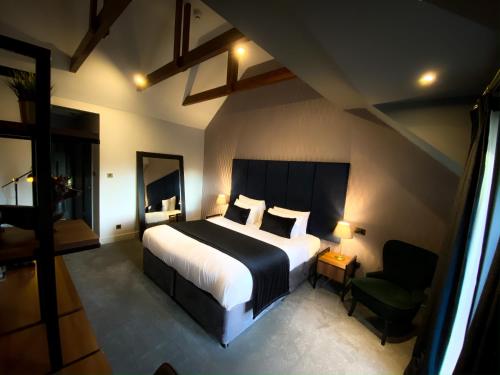 a bedroom with a large bed and a chair at The Chesterton Hotel in Bicester