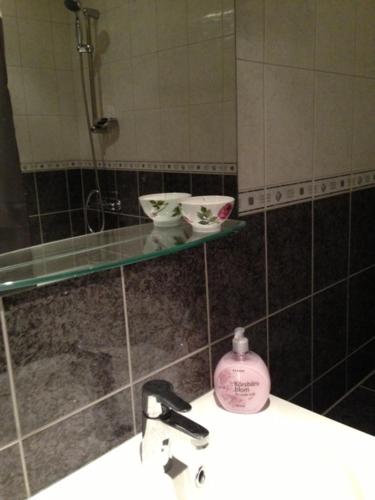 a bathroom with a sink with a mirror and a soap bottle at Pråmkanalens Pensionat i Karlstad in Karlstad