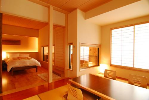 a bedroom with a bed and a table and chairs at AKARI et KAORI formerly Taizanso in Izu