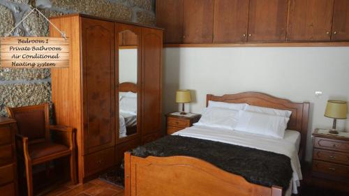 1 dormitorio con cama de madera y espejo en Quinta da Várzea de Cima en Marco de Canavezes