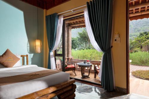 a bedroom with a bed and a view of a patio at An's Eco Garden Resort in Ninh Binh
