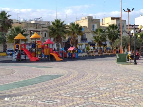 une aire de jeux dans une ville avec des équipements de jeux colorés dans l'établissement Arzella Holiday Home, à Birżebbuġa