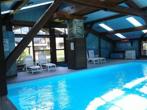 une grande piscine avec des chaises dans un bâtiment dans l'établissement La clé des montagnes, aux Houches