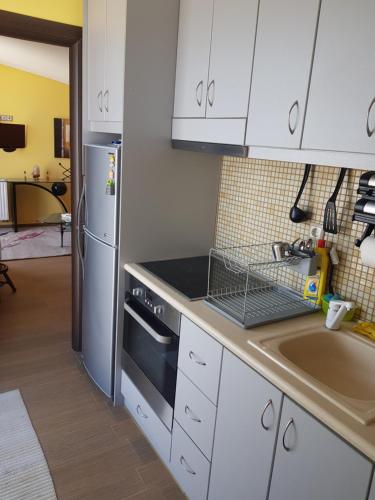 a kitchen with white cabinets and a sink and a refrigerator at VILLA BY THE SEA VRAVRONA LOUTSA(NEAR THE AIRPORT&METROPOLITAN) in Athens