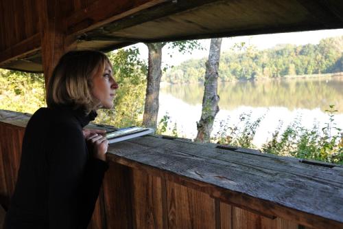 a woman standing in a boat looking at a lake at Zythogite, 23 personnes, 9 chambres, 6 salles de bain, bbq, jacuzzi, jardin, billard in Tintigny
