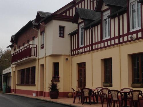 a building with tables and chairs on a street at Hotellerie Normande in Dozulé