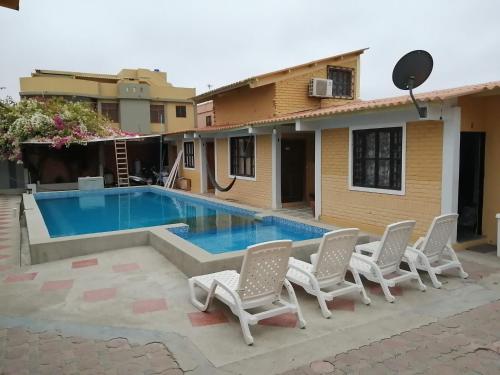 a swimming pool with chairs and a house at Casa Hospedaje Playas in Playas