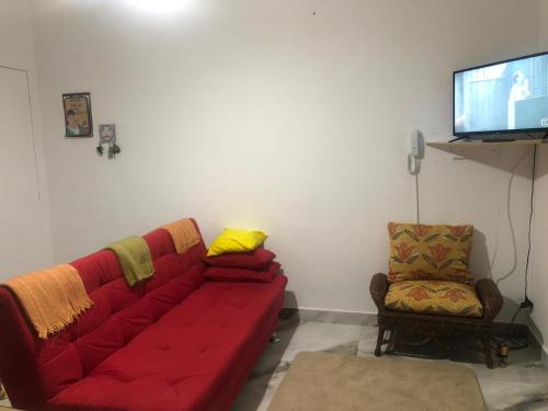 sala de estar con sofá rojo y silla en Cantinho da Lu em apt inteiro 800 mt da praia en Bertioga