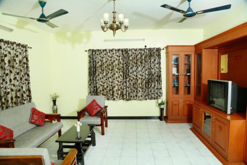 a living room with a couch and a tv at ZuriEL Suite GUEST HOUSE in Coimbatore