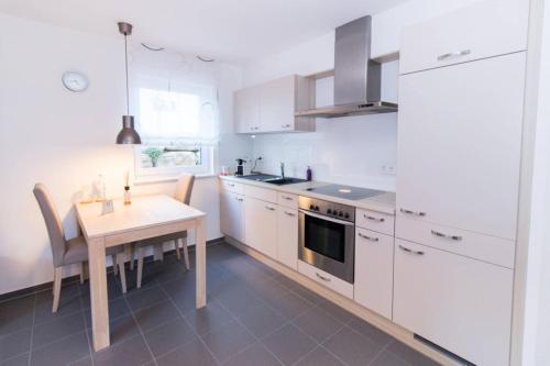 uma cozinha com armários brancos e uma mesa com uma sala de jantar em Appartement Neuenstadt in ruhiger Lage im Wohngebiet em Neuenstadt am Kocher