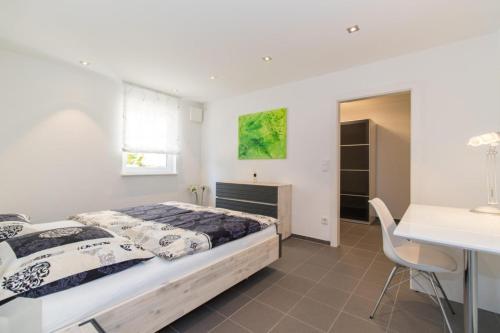 ein Schlafzimmer mit einem Bett, einem Tisch und einem Schreibtisch in der Unterkunft Appartement Neuenstadt in ruhiger Lage im Wohngebiet in Neuenstadt am Kocher