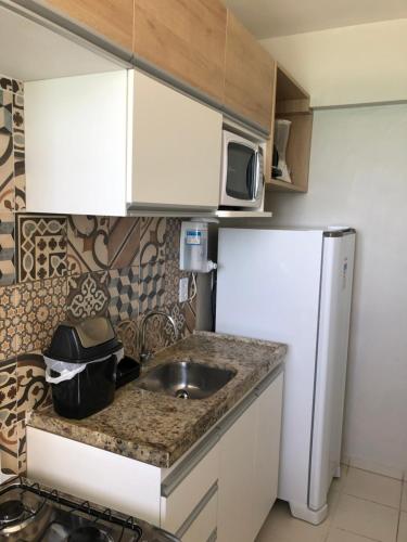 a small kitchen with a sink and a refrigerator at Apartamento 02 quartos completo, BEIRA-MAR com piscina in Maceió