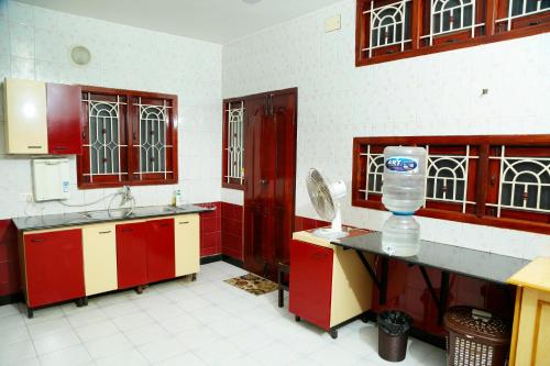 a kitchen with red cabinets and a water bottle on the counter at ZuriEL Suite GUEST HOUSE in Coimbatore