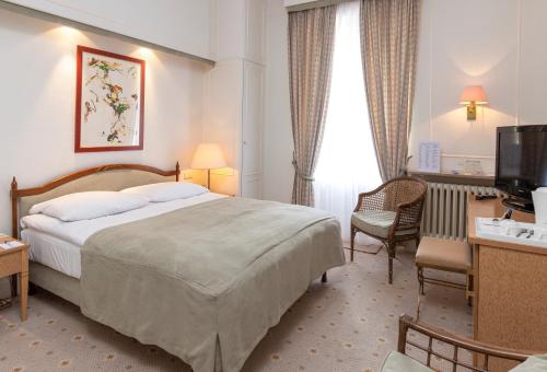 una camera d'albergo con letto e TV di Grand Hotel Cravat a Lussemburgo