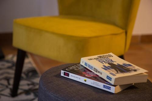 deux livres assis au-dessus d'une table avec une chaise jaune dans l'établissement En toute intimité dans le centre historique, à Montauban