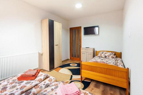 a bedroom with two beds and a tv on the wall at Erőss Kulcsosház in Lăzarea