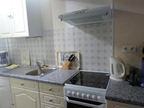 une petite cuisine avec une cuisinière et un évier dans l'établissement "Les Mouettes" Maison de pêcheur en centre ville, à Saint-Vaast-la-Hougue