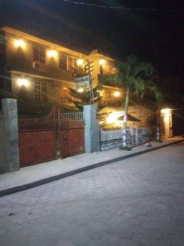 a house with a fence and a palm tree at night at La Belle Maison Milot in Samson