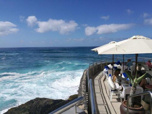 people sitting in chairs under an umbrella at the ocean at Mary's Home in Moya