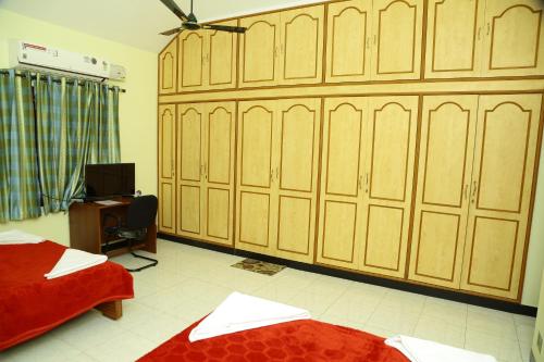 a bedroom with wooden cabinets and a bed and a desk at ZuriEL Suite GUEST HOUSE in Coimbatore