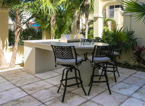 a table with four chairs and a laptop on a patio at Windsong on the Reef in Grace Bay