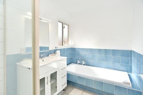 a bathroom with a white sink and a tub at City Haven - 4BR for Families & Friends, Secure Parking in Christchurch
