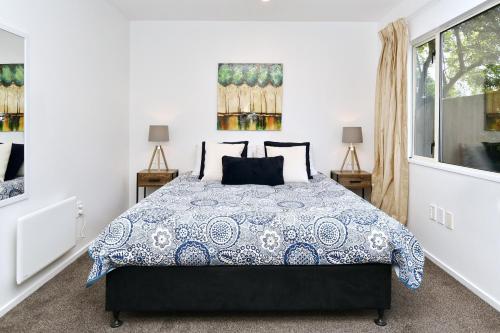 a bedroom with a bed with a blue and white comforter at City Haven - 4BR for Families & Friends, Secure Parking in Christchurch