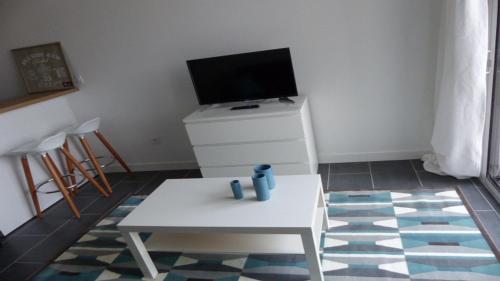 Il comprend un salon doté d'une table blanche et d'une télévision. dans l'établissement STUDIO QUAIS 2 Les MINIMES, à La Rochelle