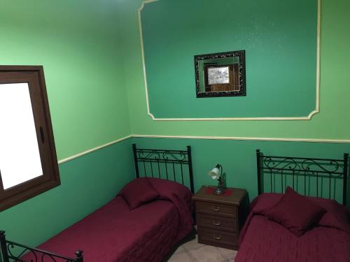 two beds in a room with green walls at Villafiorita in Gioiosa Marea