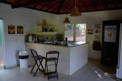 a kitchen with two chairs and a counter in a room at Pousada Encanto da Mata - Ecológica in Caconde