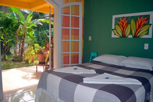 - une chambre avec un lit et un mur vert dans l'établissement Pousada Capim Melado, à Ubatuba