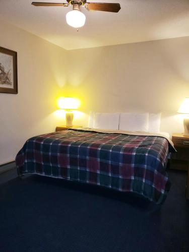 a bedroom with a bed with a plaid blanket and two lamps at North Ironwood Acres - Black River Lodge in Ironwood