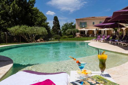 a swimming pool with a table with drinks on it at Hotel Restaurant Le Clos De Pradines in Saint-Quentin-la-Poterie