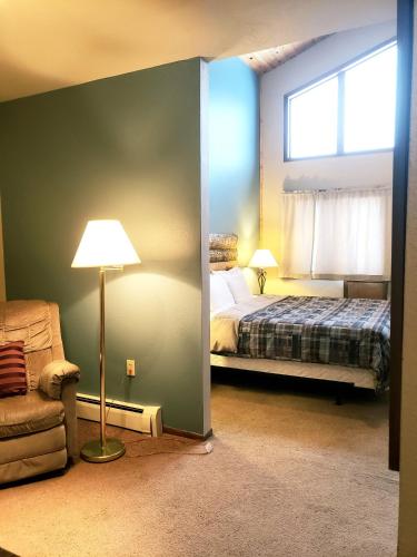 a bedroom with a bed and a lamp and a chair at North Ironwood Acres - Black River Lodge in Ironwood