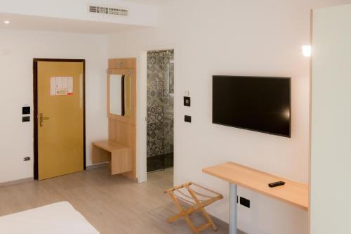 a room with a desk and a television on a wall at Hotel De Nac in Nago-Torbole