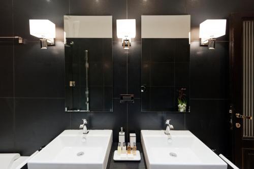 two sinks in a bathroom with two mirrors at Casa Roma Luxury Apartment in Rome