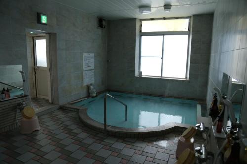 bagno con vasca e piscina di acqua di CHALET BURLAP FURANUI a Furano
