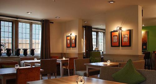 a restaurant with tables and chairs and windows at Hopping Hare in Northampton
