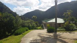 a road leading to a building with mountains in the background at Waiotemarama Falls Lodge in Opononi