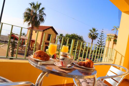 a table with a breakfast of croissants and orange juice at HOSTAL LA ESTACION in Benajarafe