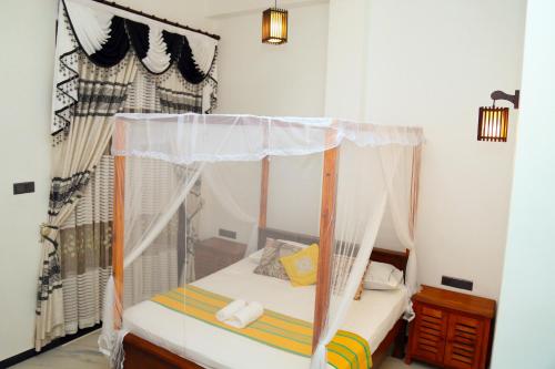a small bedroom with a bed with a canopy at Verona D' Oro in Dickwella