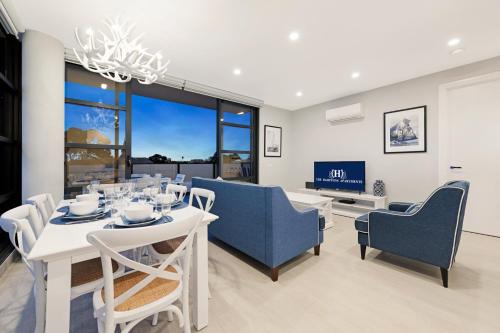 a dining room with a white table and blue chairs at The Hamptons Apartments - St Kilda in Melbourne