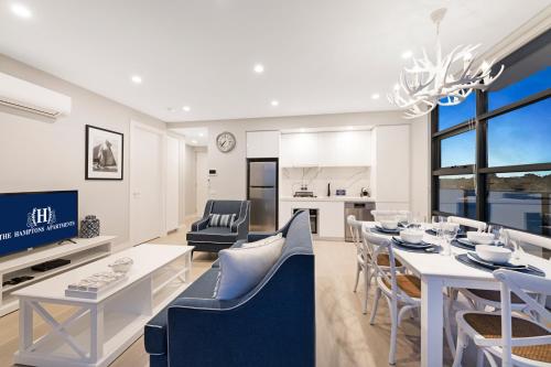 a dining room and living room with a table and chairs at The Hamptons Apartments - St Kilda in Melbourne