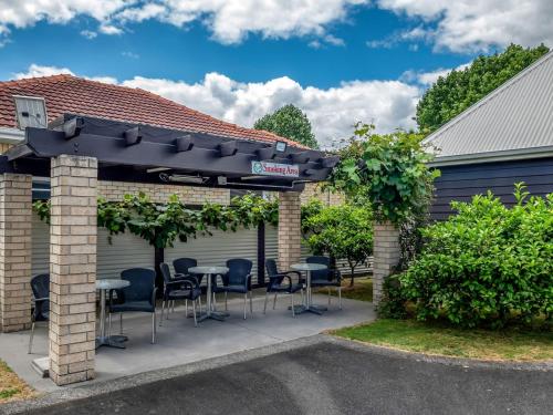 a pergola with chairs and tables in front of a house at Matamata Central Motel in Matamata