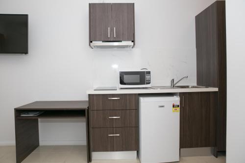 a kitchen with a refrigerator and a microwave at The Select Inn Gosford in Gosford