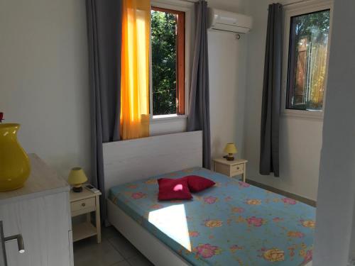 a small bedroom with a bed and two windows at Location Vacances in Deshaies
