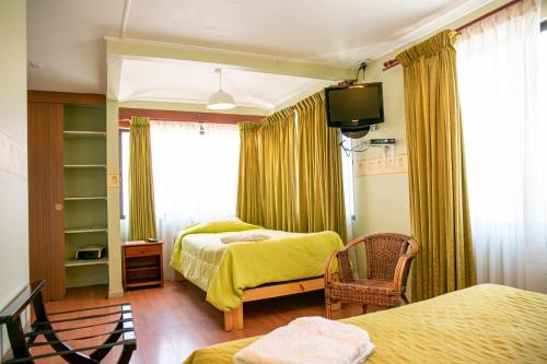 a bedroom with two beds and a television in it at Ayelen Apart Hotel in Calama